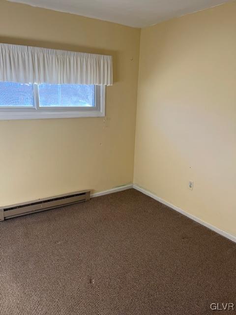 spare room with baseboards, baseboard heating, and carpet