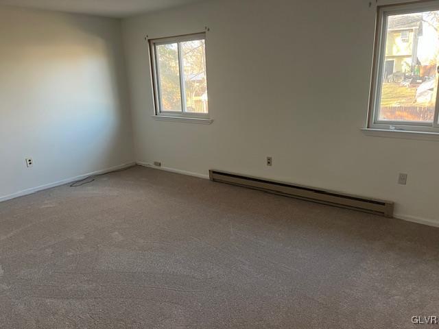 carpeted empty room with a baseboard heating unit and baseboards