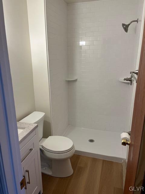 bathroom featuring a stall shower, toilet, wood finished floors, and vanity