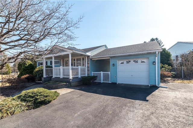 ranch-style home with fence, driveway, roof with shingles, an attached garage, and covered porch