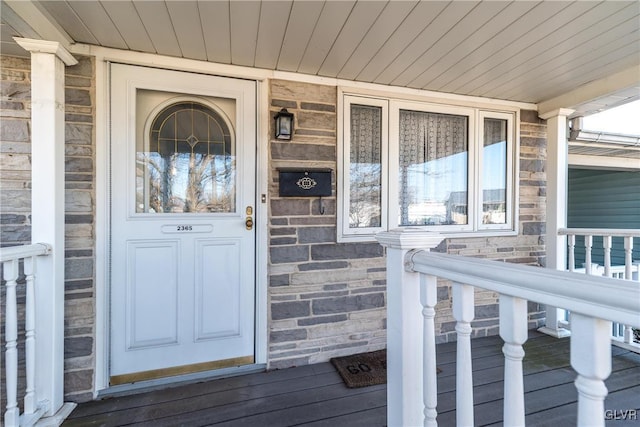 property entrance featuring covered porch and stone siding