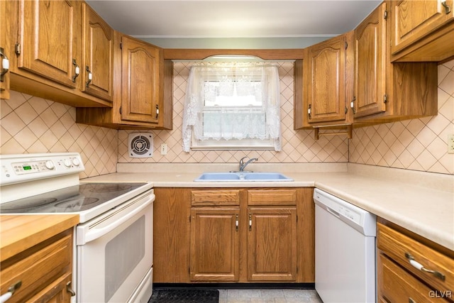 kitchen featuring decorative backsplash, white appliances, light countertops, and a sink