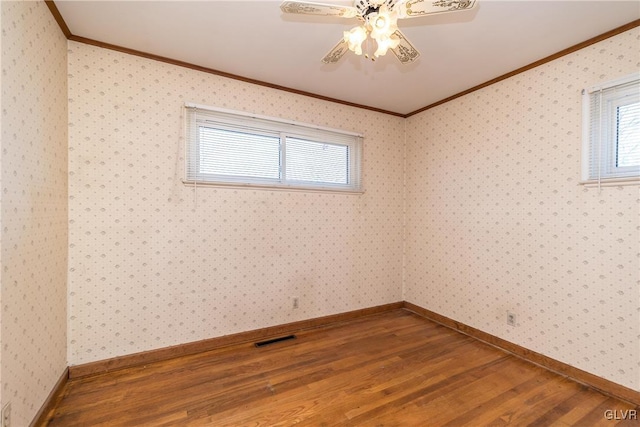 unfurnished room with visible vents, ornamental molding, wallpapered walls, and wood finished floors