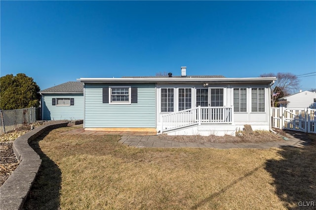 rear view of property featuring a yard and fence