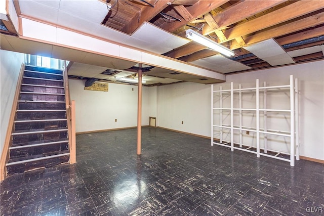 unfinished below grade area featuring tile patterned floors, stairway, and baseboards