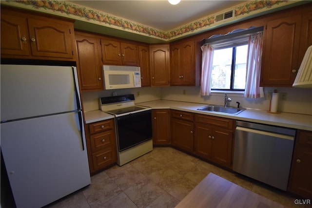 kitchen with visible vents, light countertops, brown cabinets, white appliances, and a sink