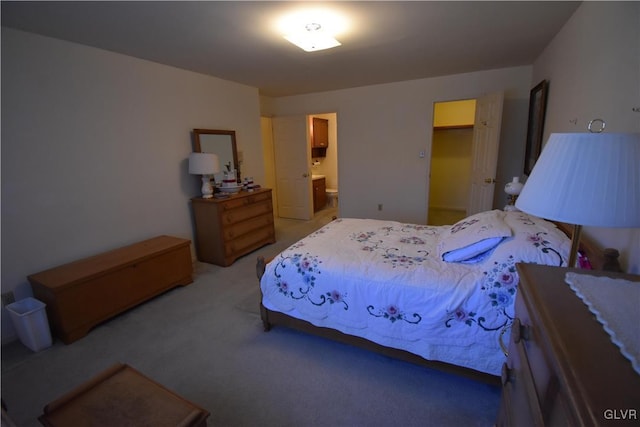 bedroom featuring light carpet and a walk in closet