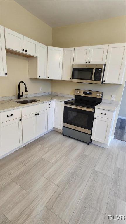 kitchen with a sink, light countertops, white cabinets, and stainless steel appliances