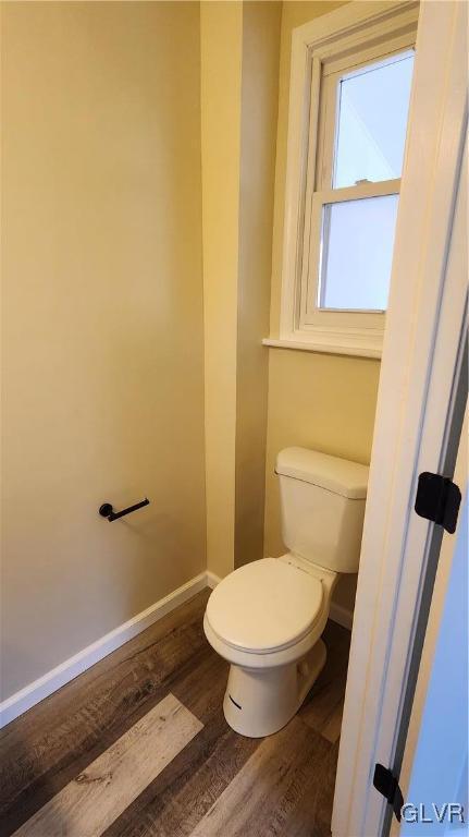 bathroom with toilet, baseboards, and wood finished floors