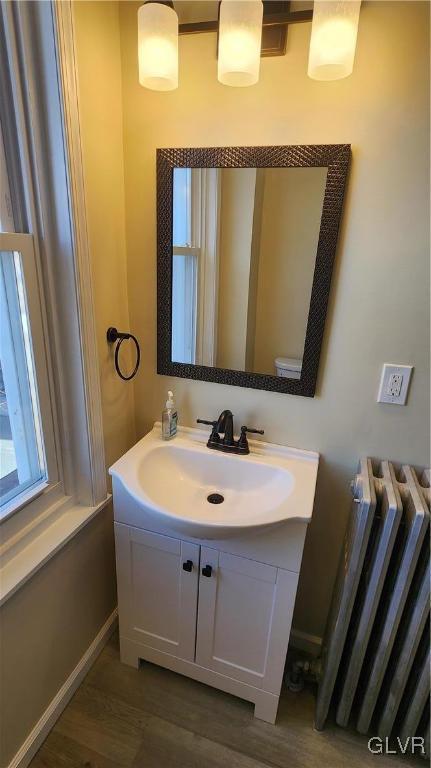 bathroom featuring vanity, radiator heating unit, baseboards, and wood finished floors