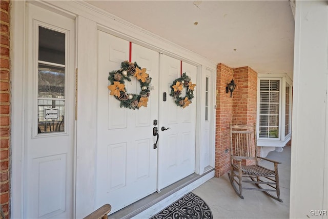 entrance to property featuring a porch and brick siding