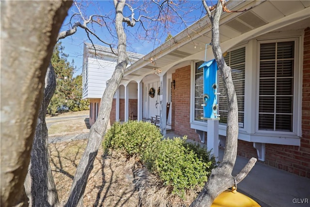 doorway to property with brick siding and covered porch