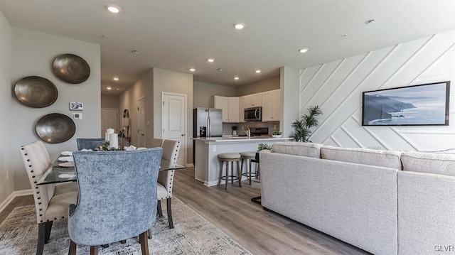 dining room with light wood-style flooring, recessed lighting, and baseboards