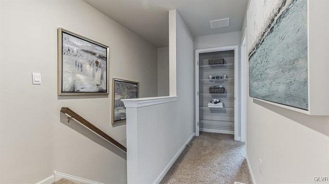 corridor featuring an upstairs landing, visible vents, carpet floors, and baseboards