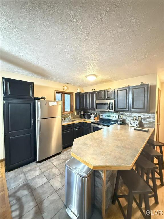 248 Penn Forest Trl, Penn Forest Township, PA 18210 - kitchen with a sink, a kitchen breakfast bar, stainless steel appliances, a peninsula, and light countertops