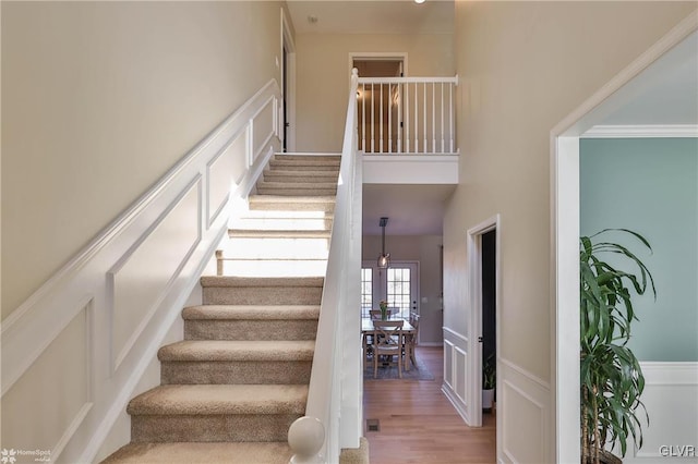 stairs featuring wood finished floors and a towering ceiling