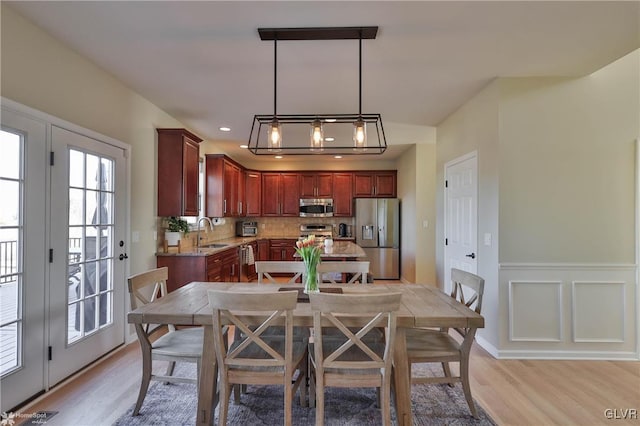 dining area featuring a decorative wall, recessed lighting, light wood-type flooring, and wainscoting