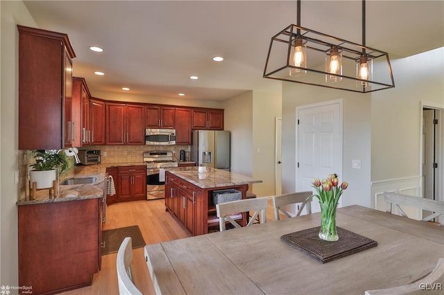 kitchen featuring light stone counters, backsplash, light wood finished floors, and stainless steel appliances