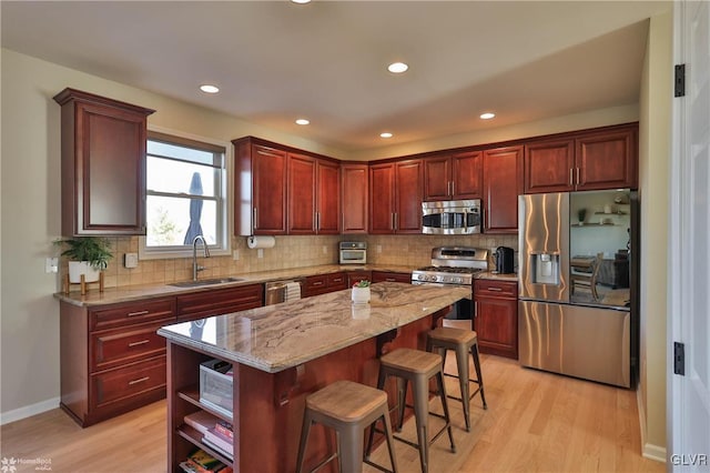 kitchen with light wood-style flooring, a sink, stainless steel appliances, dark brown cabinets, and backsplash