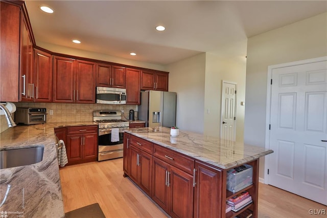 kitchen with tasteful backsplash, light wood-type flooring, appliances with stainless steel finishes, and a sink