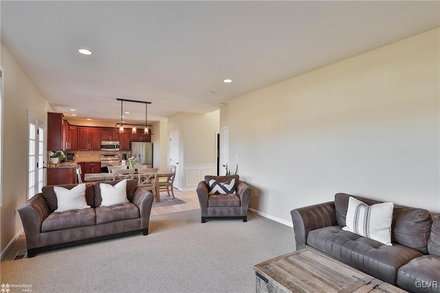 living area featuring light carpet, a decorative wall, and recessed lighting