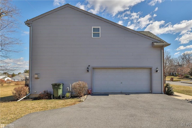 view of side of property featuring aphalt driveway, a lawn, and a garage