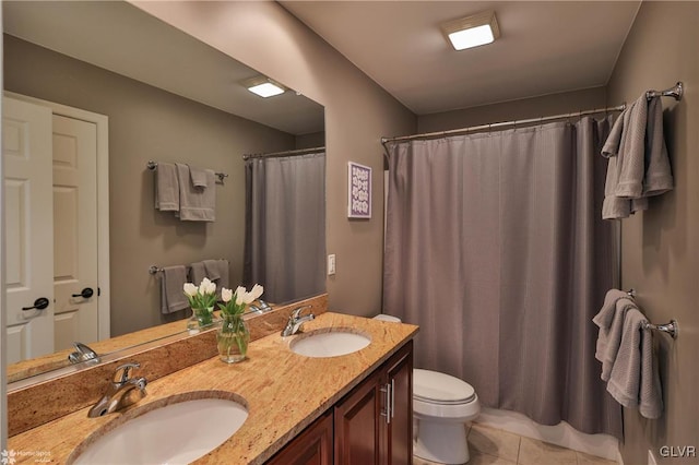 full bathroom featuring a sink, toilet, double vanity, and tile patterned flooring