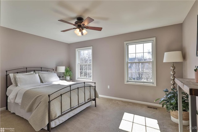 carpeted bedroom with visible vents, multiple windows, a ceiling fan, and baseboards