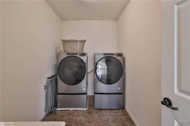 laundry area featuring baseboards, separate washer and dryer, dark tile patterned floors, and laundry area