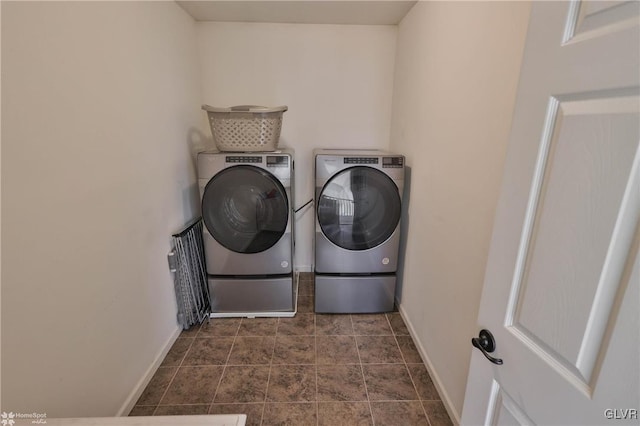 laundry room featuring baseboards, dark tile patterned floors, laundry area, and washer and clothes dryer