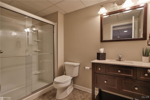 full bath with vanity, baseboards, a stall shower, a paneled ceiling, and toilet