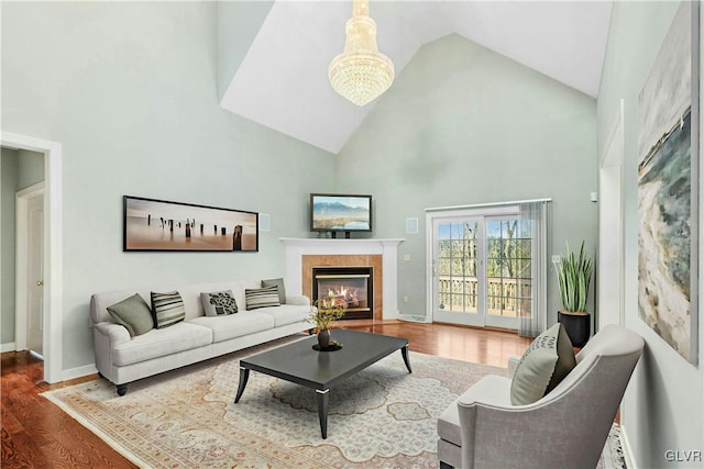 living room featuring baseboards, wood finished floors, a tile fireplace, and high vaulted ceiling