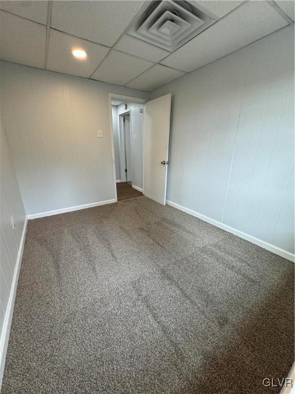 spare room with a drop ceiling, carpet floors, and baseboards