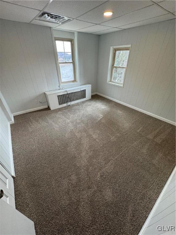 empty room featuring carpet flooring, a healthy amount of sunlight, and a paneled ceiling