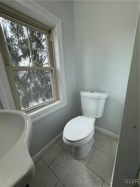 bathroom featuring tile patterned floors, baseboards, toilet, and a sink