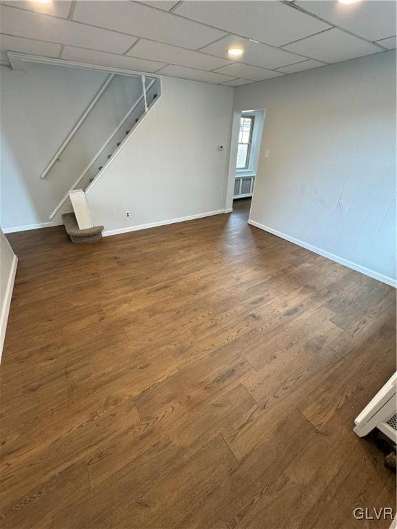 empty room featuring wood finished floors, stairs, and radiator heating unit