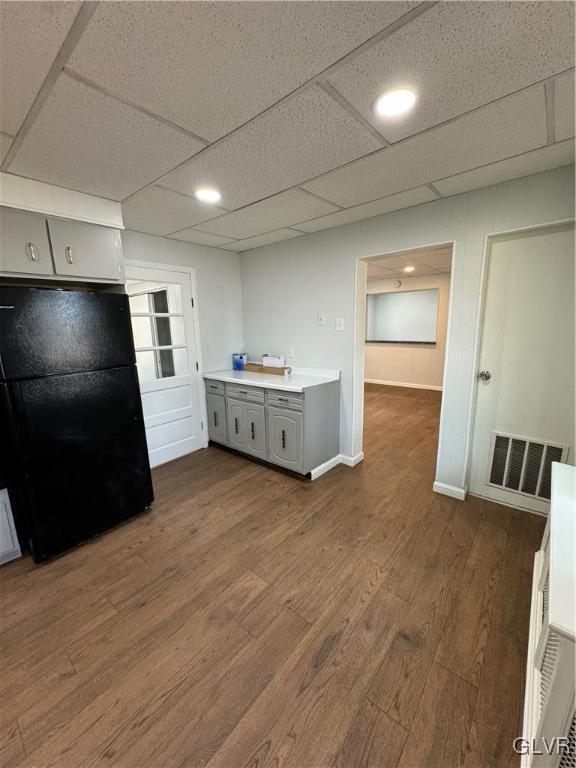 kitchen featuring dark wood-style floors, visible vents, freestanding refrigerator, gray cabinetry, and light countertops