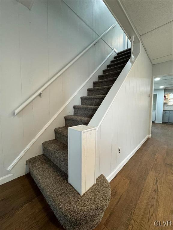 staircase with a decorative wall and wood finished floors