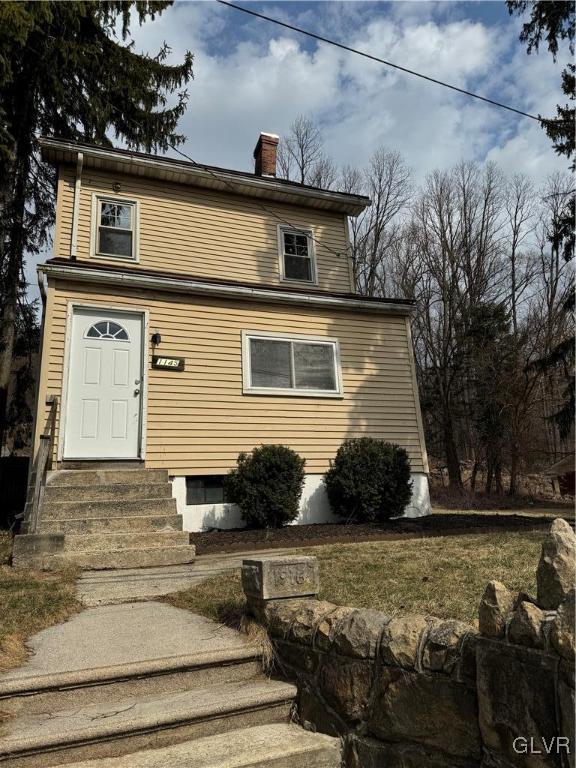 view of front facade featuring a chimney and entry steps