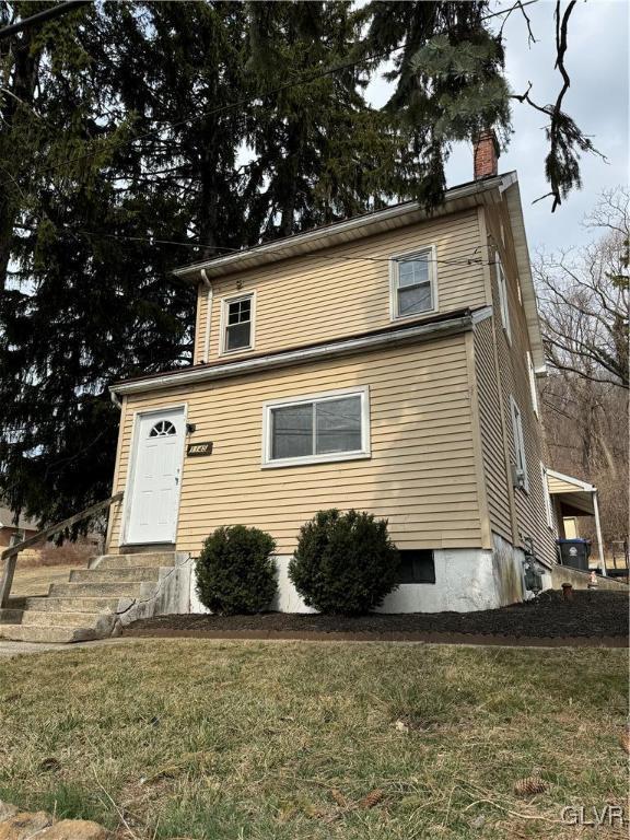 view of front facade featuring a chimney and a front yard