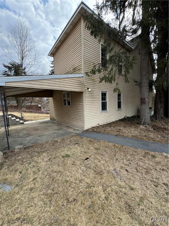 view of side of home with an attached carport and driveway