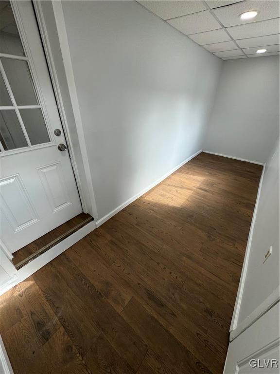 spare room with a drop ceiling, baseboards, and wood finished floors