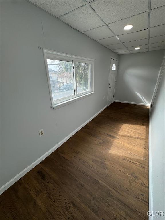 empty room featuring recessed lighting, wood finished floors, baseboards, and a paneled ceiling