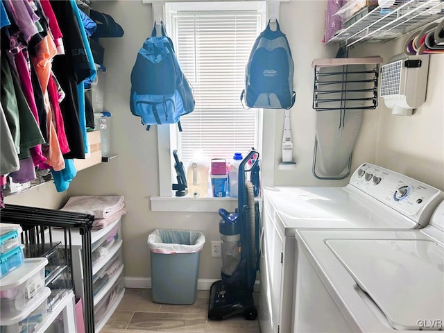 clothes washing area with laundry area, wood tiled floor, baseboards, and washer and clothes dryer