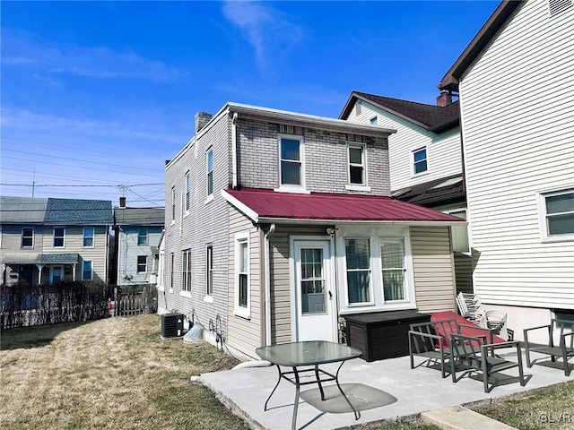 rear view of house with fence, central AC unit, metal roof, a yard, and a patio area