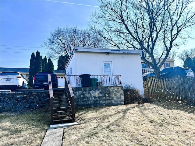 exterior space with concrete block siding, stairway, and fence