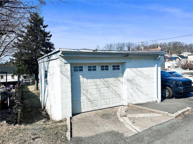 detached garage featuring driveway and fence