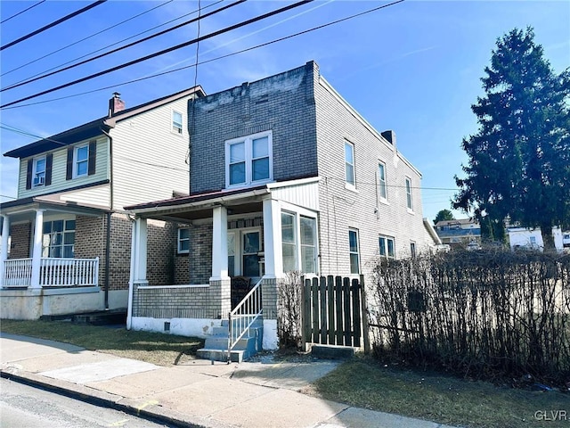 view of front of property featuring a fenced front yard, a porch, and a chimney