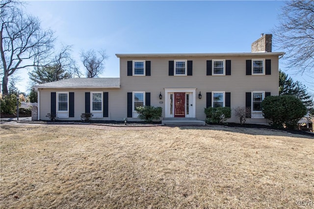 colonial home featuring a front lawn and a chimney