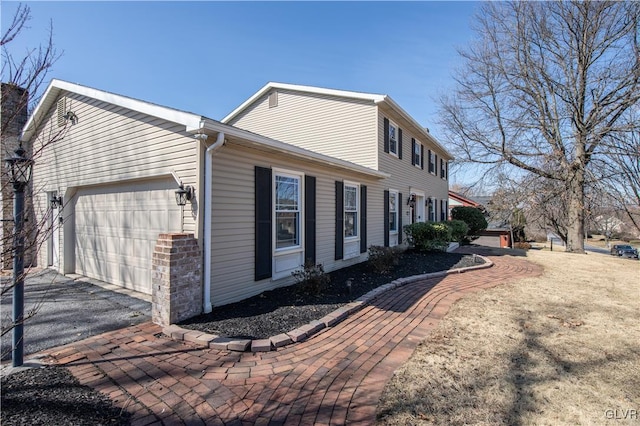 view of side of property with aphalt driveway and an attached garage